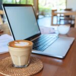 Business owner reviewing website analytics and AI search visibility metrics on a laptop with SEO reports and content planning notes in a modern home office.