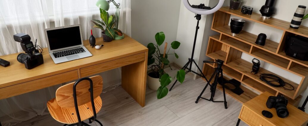 Content creator workspace with a phone tripod, laptop stand, microphone, coffee mug, and productivity tools used to create online content.
