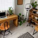 Content creator workspace with a phone tripod, laptop stand, microphone, coffee mug, and productivity tools used to create online content.