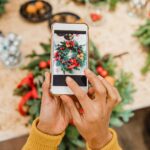 Small business owner planning holiday marketing content with a notebook, laptop, calendar, coffee, and Christmas inspiration on
