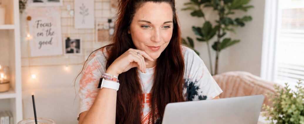 Business owner researching Pinterest keywords on a laptop before designing a Pin, with a notebook and coffee nearby.