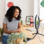 Content creator working at a desk with a laptop and camera