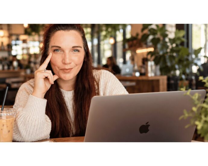 Blogger working on a laptop with a notebook and coffee on a desk.