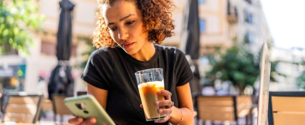 Content creator looking at her phone while working at a coffee shop.