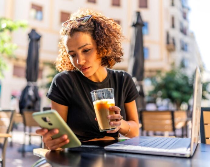 Content creator looking at her phone while working at a coffee shop.